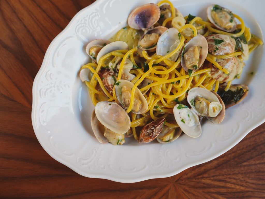 A savory Italian pasta dish with fresh clams served on a decorative white plate, perfect for seafood lovers.
